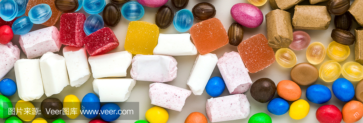 彩色的焦糖旗散落在桌子的背景上。糖的产品。彩色的糖果